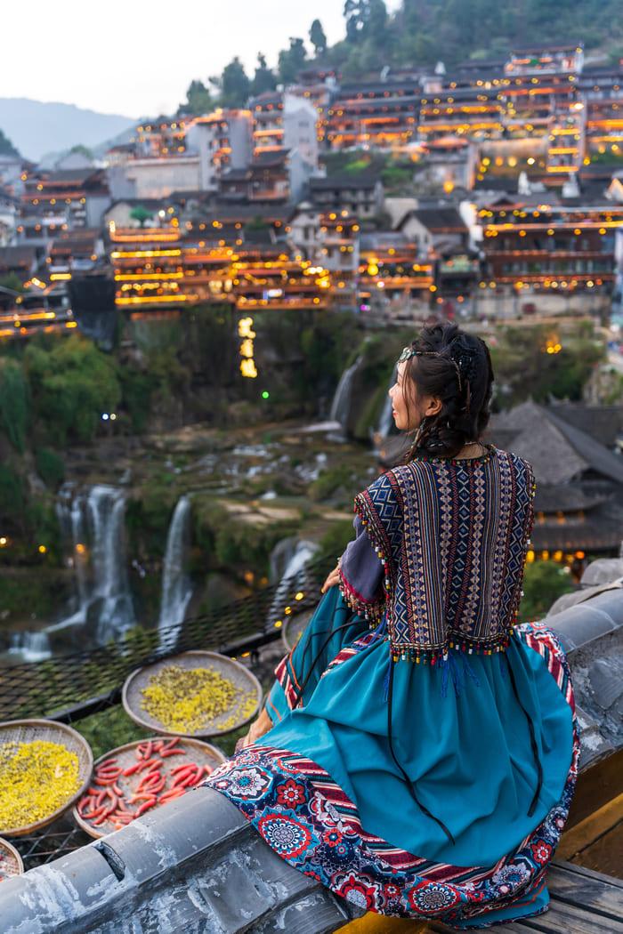 Chica con ropa tipica de china observando el paisaje de la ciudad de lijiang
