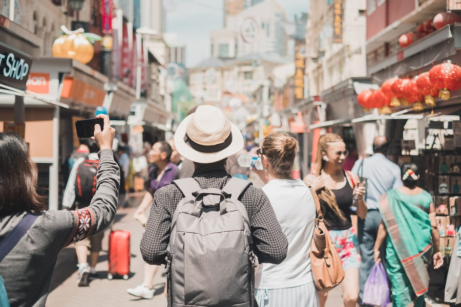 viajero de espaldas en China, lleva un sombrero.y una mochila beige. Hay más turistas al rededor